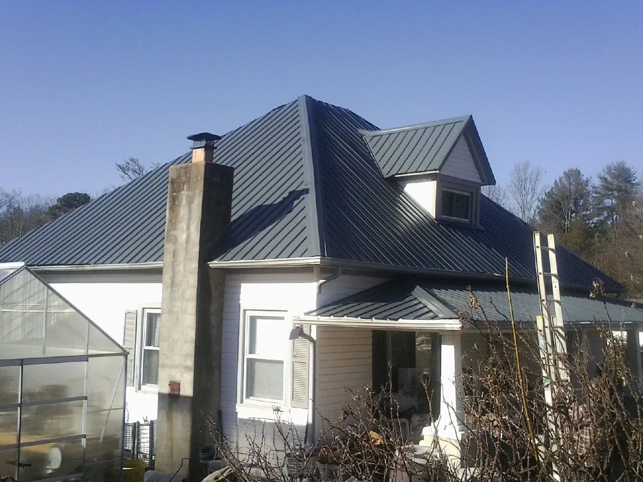 Dark blue standing seam metal roof on a white farmhouse with dormer — Slate & Tile Roof Repair by Roofing Brothers in Mechanic Falls