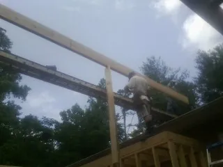 Carpenter setting a ridge beam over a new addition frame — Ice Dam Removal by Roofing Brothers in Mechanic Falls