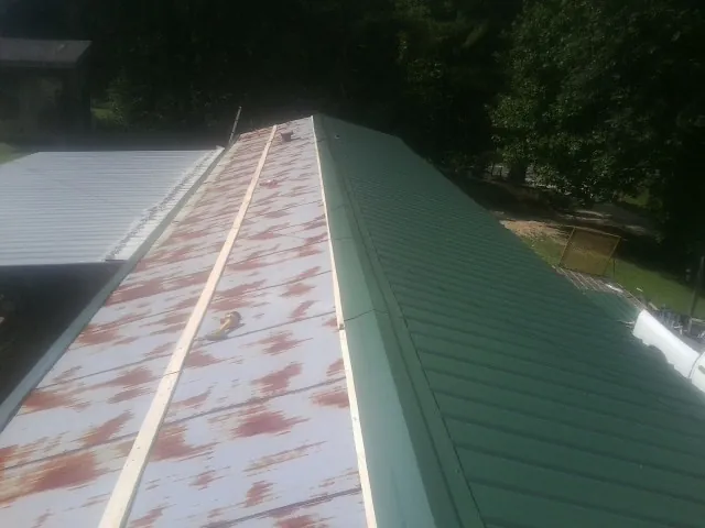 Old rusted panels beside newly installed green metal roofing — Wind Damage Roof Repair by Roofing Brothers in Mechanic Falls