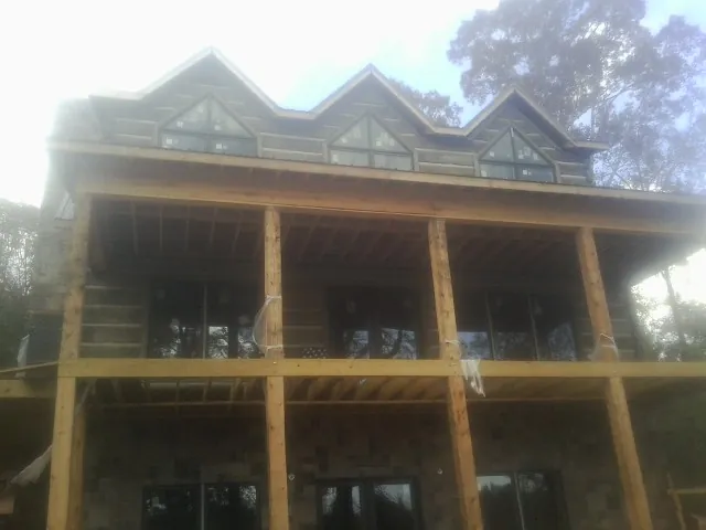 Dormers and porch framing on a large log home under construction — Roof Coating work by our crew in Mechanic Falls