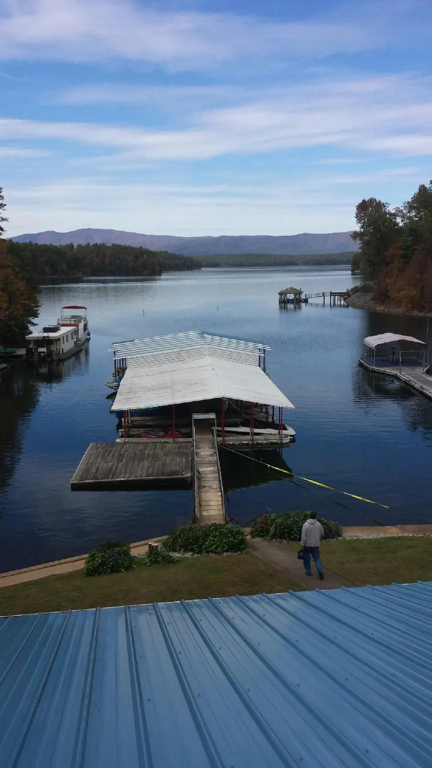 View across a lake from a newly installed blue metal roof in Mechanic Falls