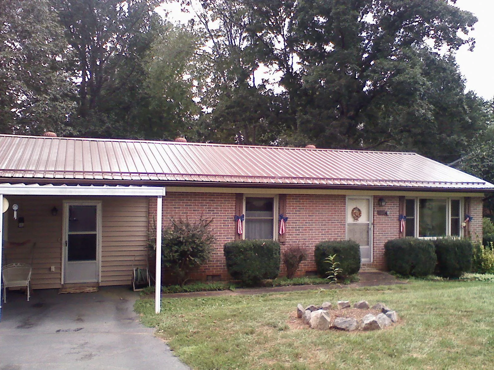 Bronze metal roof and carport on a brick ranch home — Roof Repair work by our crew in Mechanic Falls