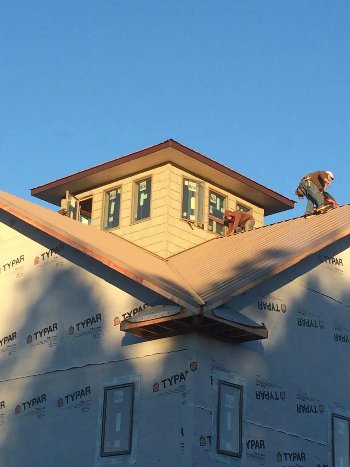 Roofers working around a rooftop cupola on a new metal roof at sunset — Roof Waterproofing in Mechanic Falls by Roofing Brothers